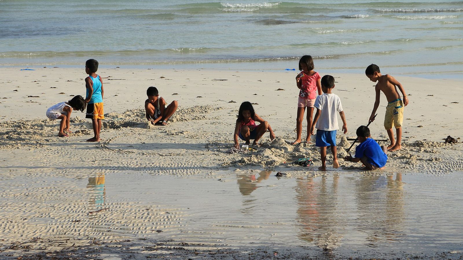 Kinderen spelen in het ondiepe water op het strand
