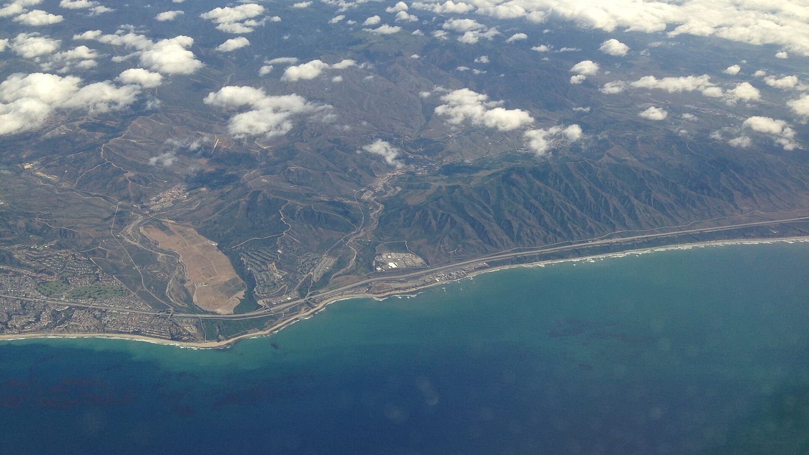 Uitzicht vanuit het vliegtuigraam op de kust